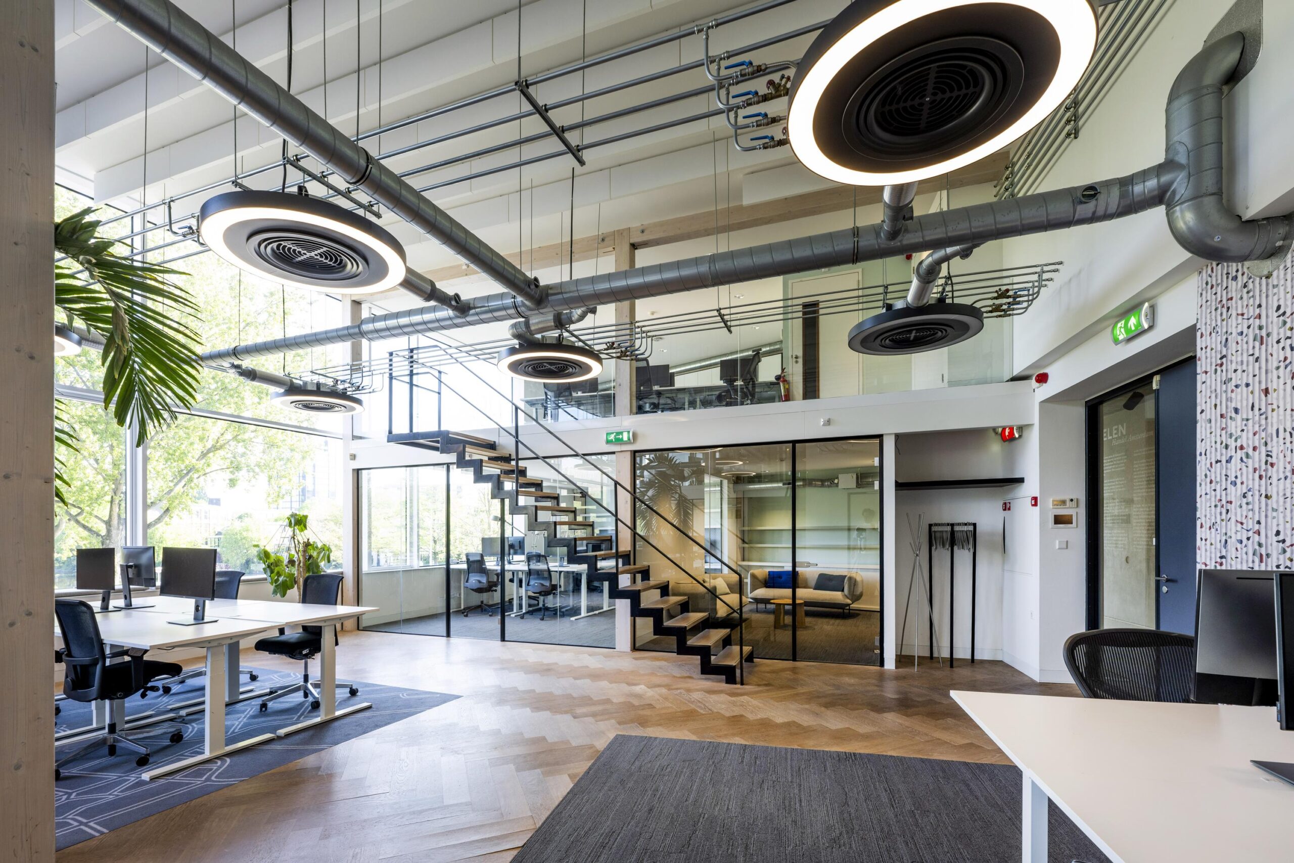 Moderne, open kantoorruimte aan de Fred. Roeskestraat met glazen wanden, industriële plafondleidingen en een stalen trap.